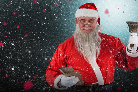 Santa Claus holding envelopes and bell against snow with red flakesの写真素材