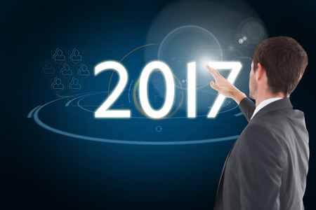 Focused businessman standing and pointing against blue background with vignette