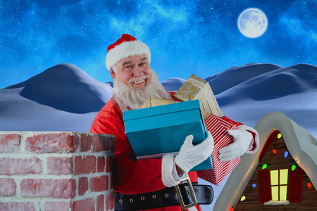 Portrait of Santa Claus carrying various gifts against winter snow sceneの写真素材