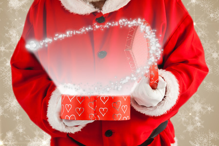 Santa claus opening a gift box against white snowflake design on creamの写真素材
