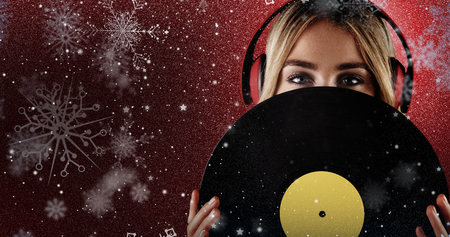 Portrait of a beautiful woman holding a vinyl  against snowの写真素材
