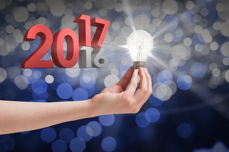 Hand holding light bulb against glowing background