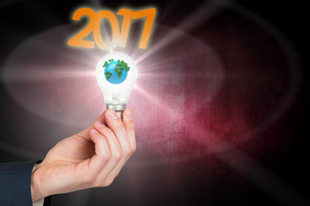Hand holding environmental light bulb against dark background