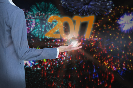 Businesswoman presenting against colourful fireworks exploding on black backgroundの写真素材