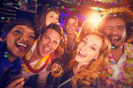 Group of friends having fun in bar against flying coloursの写真素材