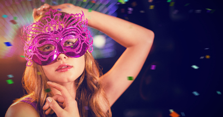 Woman posing with masquerade in bar against flying coloursの写真素材
