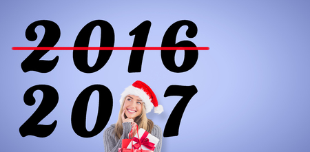 Festive blonde holding christmas gift and bag against purple backgroundの写真素材