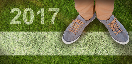 Low section of man wearing shoes  against closed up view of grassの写真素材