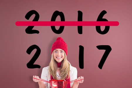 Pretty blonde opening gift bag against room with wooden floor