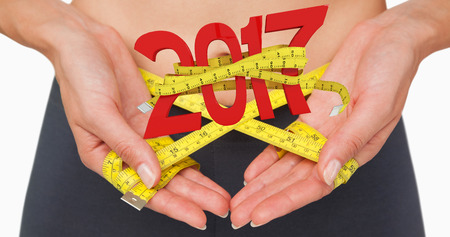 3D Close-up mid section of a woman measuring waist against new year with tape measureの写真素材