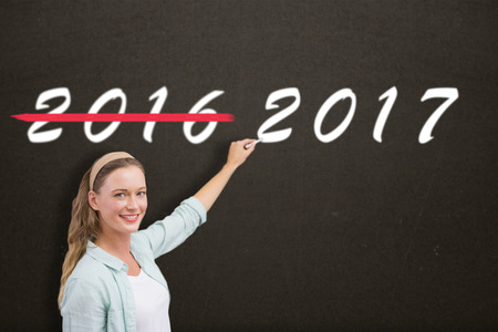 Smiling teacher writing over white background against dark roomの写真素材