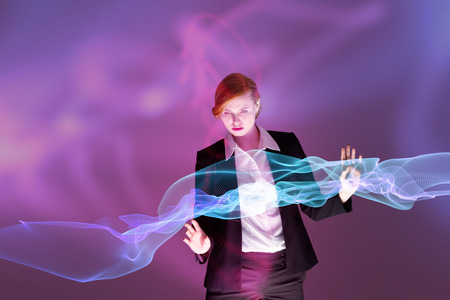3D Redhead businesswoman using interactive desk against futuristic shiny black backgroundの写真素材