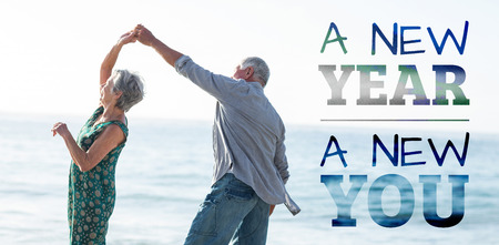 New year new you against senior couple dancing at beachの写真素材