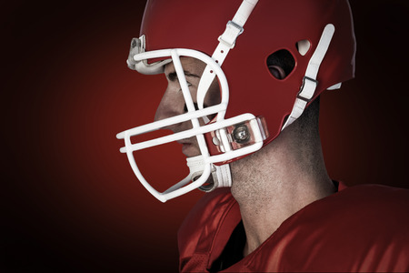 Side view of rugby player wearing gears against red background with vignetteの写真素材