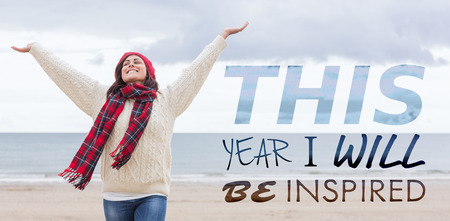 Woman in warm clothing stretching arms on beach against this year i will be inspiredの写真素材