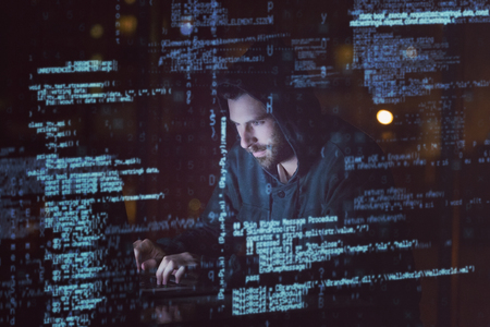 3D Hacker using laptop in dark roomの写真素材