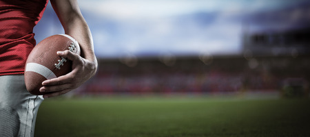 3D Cropped image of sportsman holding American football against gloomy skyの写真素材