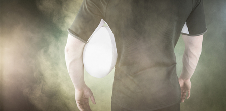 3D Rugby player holding a rugby ball against splashing of yellow color powderの写真素材
