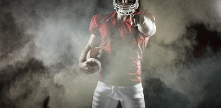 3D American football player pointing at camera against splashing of powderの写真素材