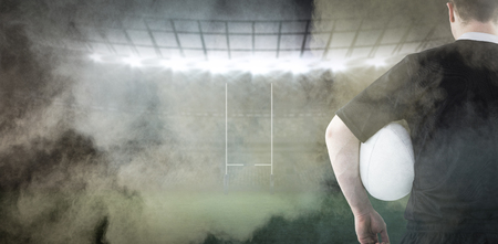 3D Rugby player holding a rugby ball against splashing of powderの写真素材