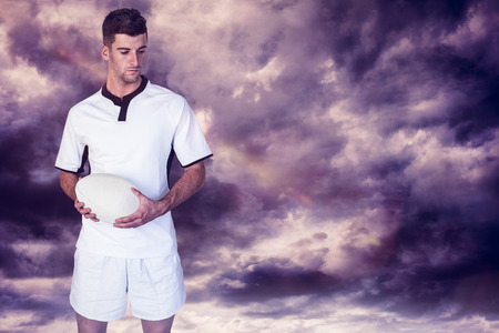 3D Rugby player holding the ball against gloomy skyの写真素材