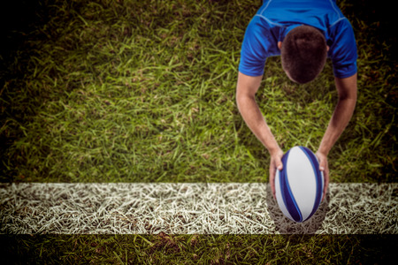 3D Rugby player lying in front with ball against grassの写真素材