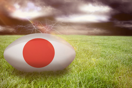 3D japan rugby ball against stormy sky over large cityの写真素材