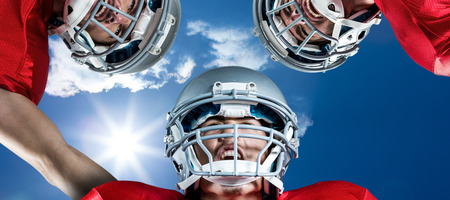 3D American football huddle against bright blue sky with cloudsの写真素材