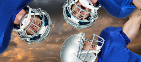 3D American football huddle against blue and orange sky with cloudsの写真素材