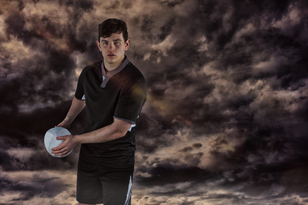 3D Rugby player about to throw the rugby ball against gloomy skyの写真素材