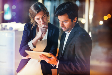 3D Businessman discussing with colleague over digital tablet in officeの写真素材