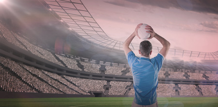 3D Rugby player holding a rugby ball against rugby stadiumの写真素材