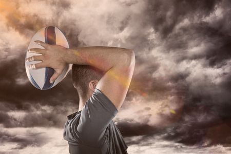 3D Rugby player throwing ball against gloomy skyの写真素材