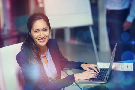 Portrait of businesswoman working on laptop in officeの写真素材