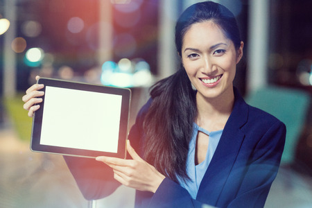 Portrait of businesswoman showing digital tablet in officeの写真素材