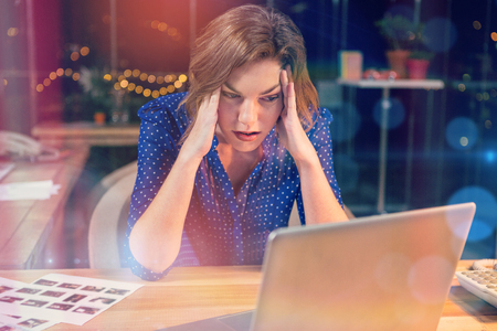 Stressed businesswoman sitting at desk in officeの写真素材