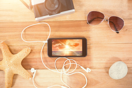 Beach accessories on wooden board against sunrise over magical seaの写真素材