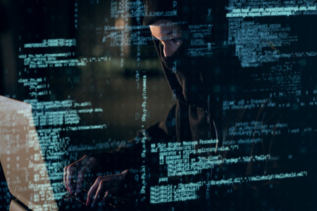 Woman in balaclava using laptop in office 3Dの写真素材