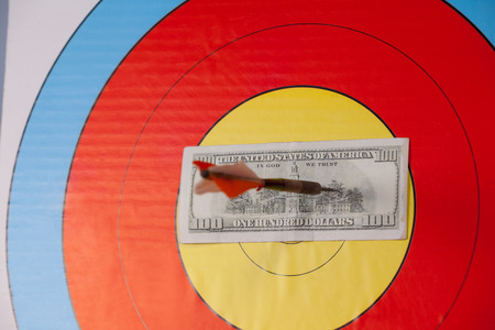 Close-up of darted hundred dollars on dart boardの写真素材