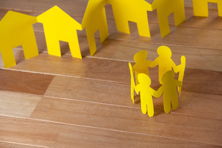 Conceptual image of paper cutout people standing in a circle against paper housesの写真素材