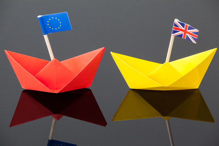 Close-up of two paper boats with union jack and european union flagの写真素材