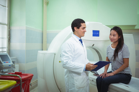 Doctor and patient discussing over clipboard in the hospital