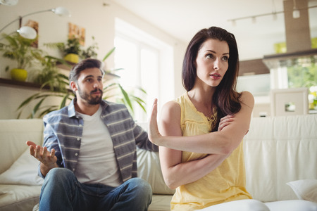 Upset couple arguing with each other on sofa in living roomの写真素材