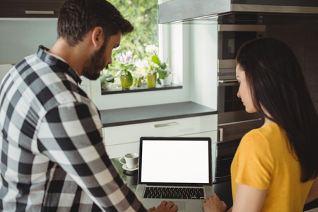 Couple using laptop in the kitchen at homeの写真素材