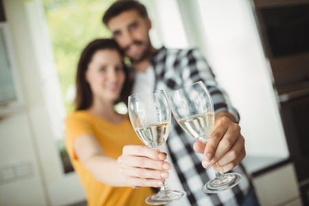 Happy couple toasting glasses of champagne in kitchenの写真素材