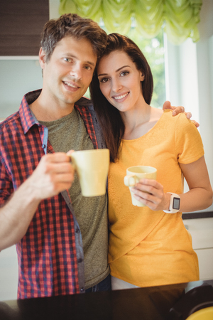 Portrait of happy couple having coffee in kitchen at homeの写真素材