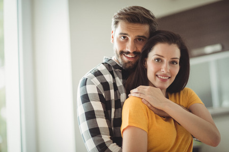Portrait of happy couple embracing in kitchen at homeの写真素材