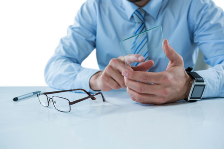 Mid section of businessman sitting at table touching a glass sheetの写真素材