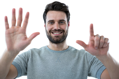 Smiling man pretending to touch an invisible screen against white backgroundの写真素材