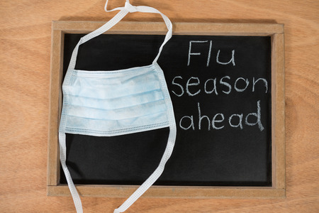 Close-up of flue season ahead written on chalk board with medical maskの写真素材